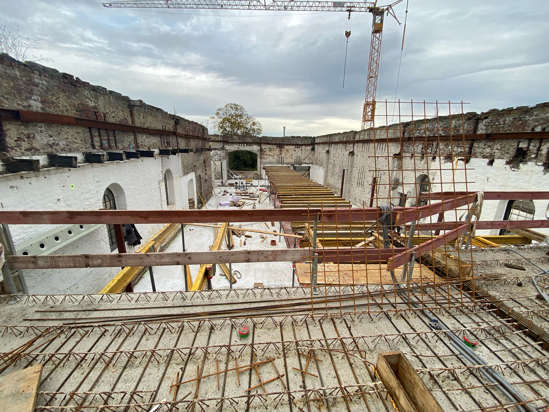 austelle mit Betonwänden und einem Kran, der über die Baustelle schwebt, um Materialien zu heben.